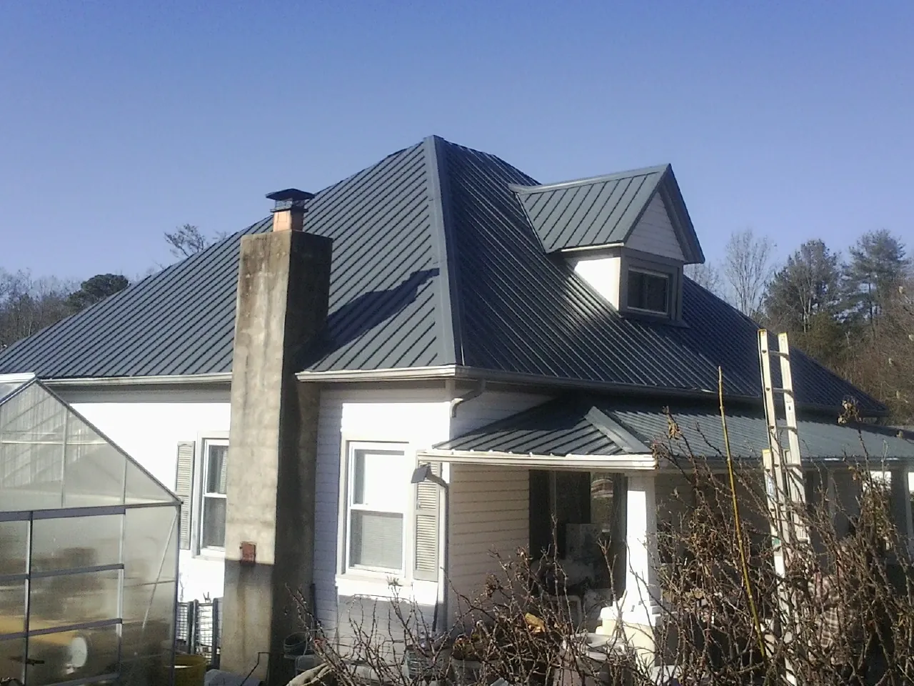 Dark blue standing seam metal roof on a white farmhouse with dormer — Slate & Tile Roof Repair by Roofing Brothers in Bowdon