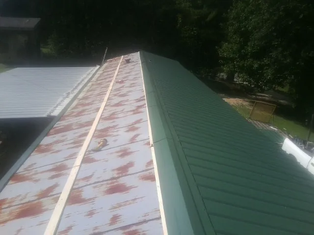 Old rusted panels beside newly installed green metal roofing — Wind Damage Roof Repair by Roofing Brothers in Bowdon
