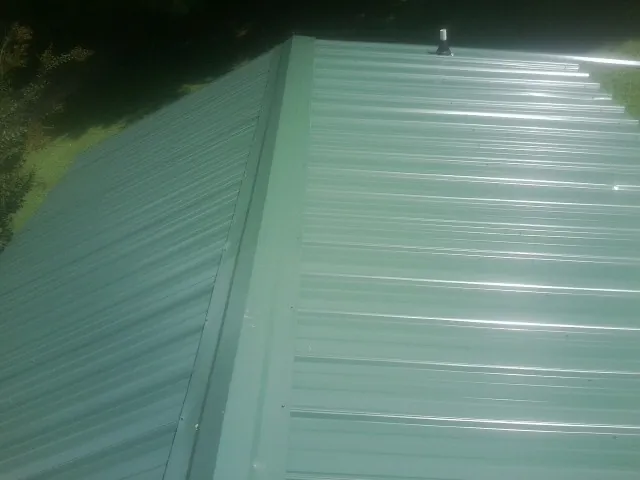New green metal panels meeting at the ridge of a roof — Flat Roof Repair work by our crew in Bowdon