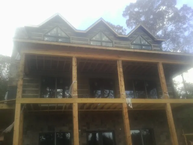Dormers and porch framing on a large log home under construction — Roof Coating work by our crew in Bowdon