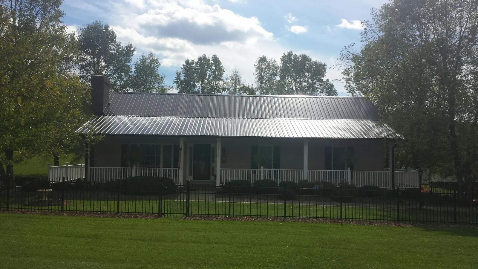 Gray metal roof on a brick ranch with a full width front porch — Gutter Guard Installation work by our crew in Bowdon
