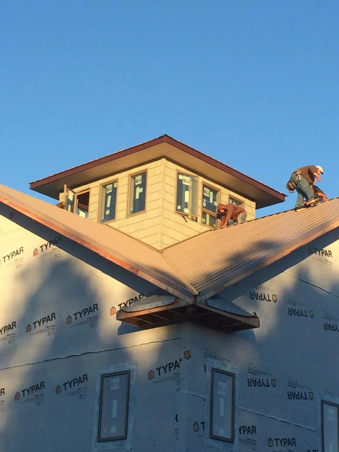 Roofers working around a rooftop cupola on a new metal roof at sunset — Roof Waterproofing in Bowdon by Roofing Brothers